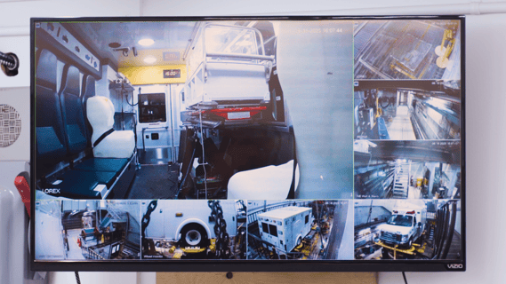 Display showing multiple camera feeds of an ambulance on a vibration test platform for neonatal transport research.