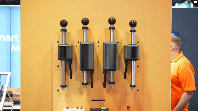 GIF of four ORCA™ Smart Linear Motors moving up and down vertically on an orange exhibition display board