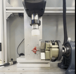 [GIF] side view of a testing mechanism holding a red router bit in a motorized chuck below a vertical plunger