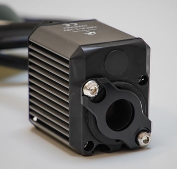 Angled view of an ORCA motor showing the black bushing retainer installed around the shaft opening and secured with two bolts